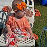 Nova Leigh is registered to the contest to win money with this photo: child, toddler, baby, sitting, outdoor, backyard, chair, orange_bow, hair_bow, cat_shirt, colorful_clothing, patterned_pants, grass, inflatables, party, sunlight, portrait, playground, furniture, family_photo