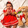 baby, child, teddy_bear, tulips, bouquet, red_dress, polka_dot, lace, smile, happy, clapping_hands, blanket, soft, cute, toy, flower, ribbon, portrait, infant, lying_down