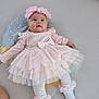 baby, infant, pink_dress, headband, tights, socks, pillow, lying_down, soft_surface, cute, adorable, child, portrait, indoor, clothing, smiling, happy, toddler, fashion, accessory