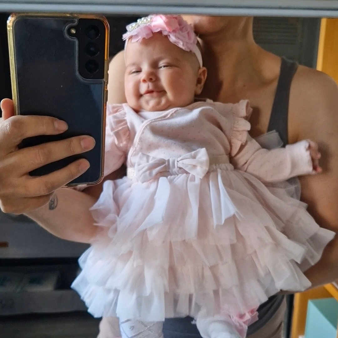 Aria Cataleya is registered to the contest to win money with this photo: adult, baby, bow, child, cute, dress, hand, happy, headband, holding, indoors, mirror, person, phone, pink, reflection, selfie, smile, socks, tulle