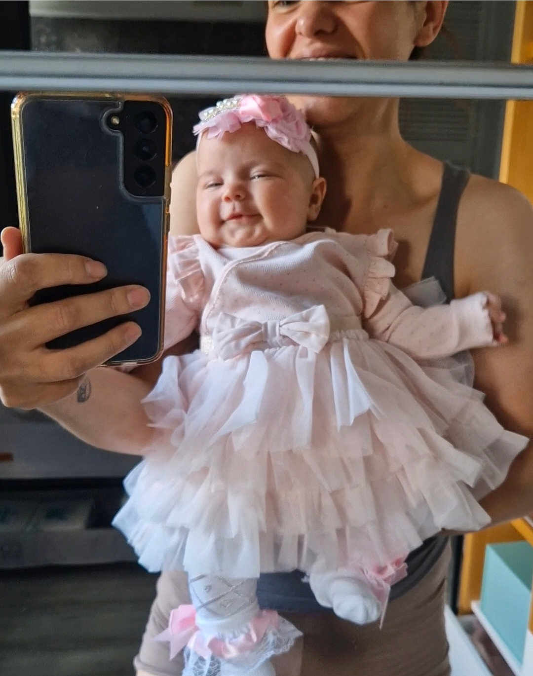 Aria Cataleya is registered to the contest to win money with this photo: baby, child, adult, mirror, selfie, dress, pink, headband, smile, hand, phone, reflection, indoors, person, holding, cute, tulle, socks, bow, happy