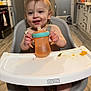 Colter is registered to the contest to win money with this photo: toddler, child, high_chair, sippy_cup, kitchen, floor, hand, food, messy, baby, smiling, plastic, furniture, cabinet, appliance, person, foot, table, drink, indoor