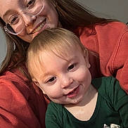 Colter joined the competition — help win amazing prizes! child, toddler, woman, glasses, smile, drool, portrait, indoor, casual_clothing, green_shirt, red_sweater, face, person, happy, closeup, baby, long_hair, light_skin, head_and_shoulders, family