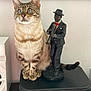 cat, tabby_cat, blue_eyes, statue, jazz_musician, trumpet, briefcase, indoor, feline, pet, animal, decor, figurine, sitting, striped, ears, whiskers, tail, furniture, household