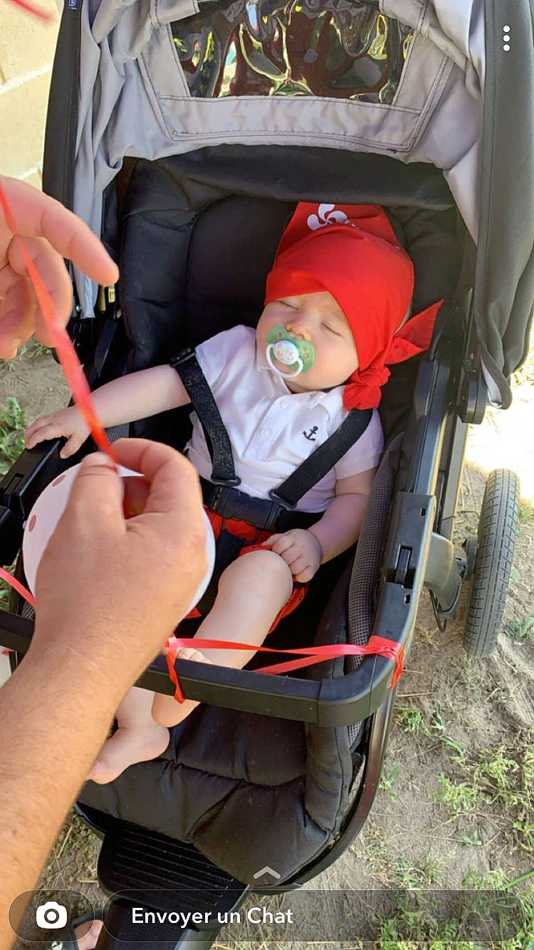 Donovan participe au concours pour gagner de l'argent avec cette photo : baby, baby_carriage, baby_products, car_seat, chair, child, comfort, fun, gesture, grass, headwear, lap, leisure, person, personal_protective_equipment, plant, recreation, sitting, tire, toddler