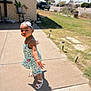 brick_wall, child, cute, daylight, dress, grass, headband, outdoor, person, plant, playful, pose, sandals, shadow, sidewalk, smile, summer, sunny, toddler, vehicle
