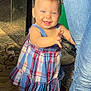 baby, child, smiling, dress, plaid, indoor, carpet, jeans, person, footwear, sock, furniture, home, light, shadow, happy, reaching, floor, standing, cute