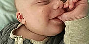 Liam is registered to the contest to win money with this photo: baby, blanket, child, close_up, comfort, cozy, cute, face, hand, indoor, infant, peaceful, portrait, resting, sleeping, smiling, soft_lighting, striped_clothing, thumb_sucking, young