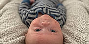 Liam is registered to the contest to win money with this photo: baby, infant, blanket, striped_clothing, face, head, eyes, skin, lying_down, cozy, soft_texture, indoor, child, person, cute, newborn, warm, comfort, portrait, closeup
