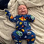 Liam is registered to the contest to win money with this photo: baby, infant, smiling, onesie, space_theme, blanket, cozy, lying_down, cute, happy, child, footed_pajamas, planet, star, colorful, sleepwear, fabric, texture, room_interior, portrait