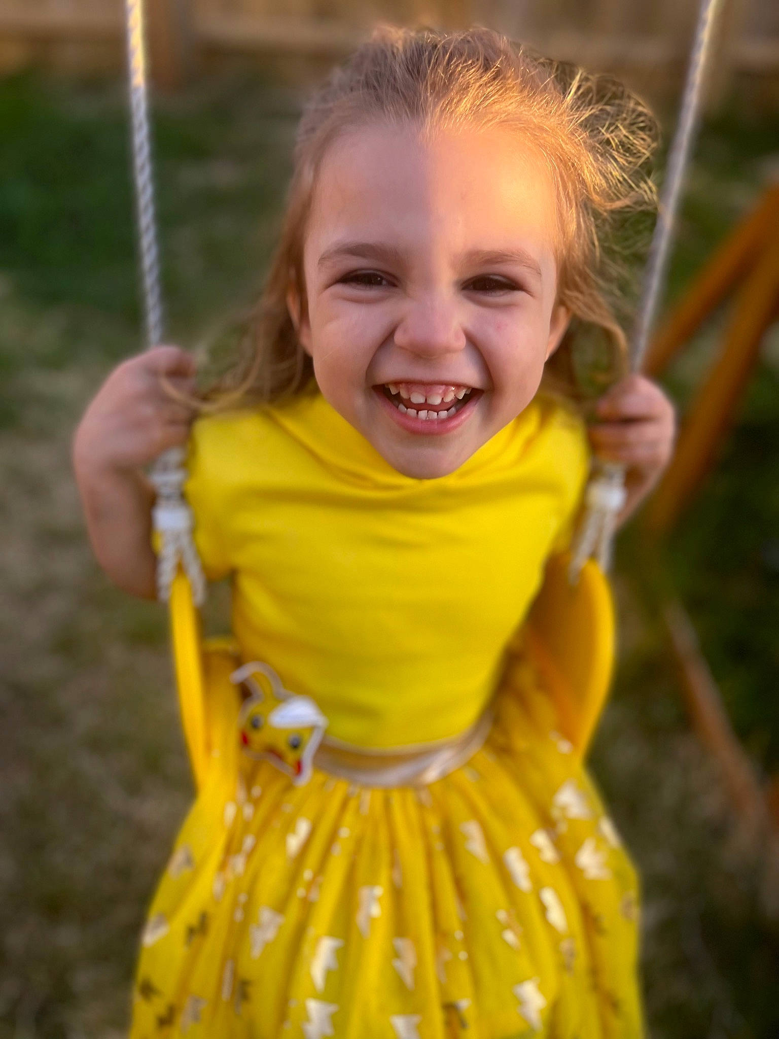 Taytum joined the competition — help win amazing prizes! baby_toddler_clothing, dress, facial_expression, fun, grass, hair, happy, head, human_body, iris, joy, one_piece_garment, people_in_nature, person, recreation, sleeve, smile, summer, sunlight, swing
