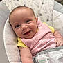 baby, smiling, infant, face, pink_bib, yellow_shirt, baby_seat, strapped_in, happy, cute, child, person, closeup, indoor, soft_fabric, disney_baby, portrait, skin, arm, young