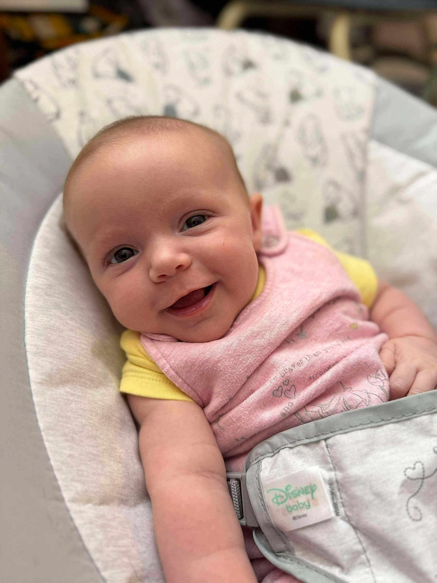 Julia joined the competition — help win amazing prizes! baby, smiling, infant, face, pink_bib, yellow_shirt, baby_seat, strapped_in, happy, cute, child, person, closeup, indoor, soft_fabric, disney_baby, portrait, skin, arm, young