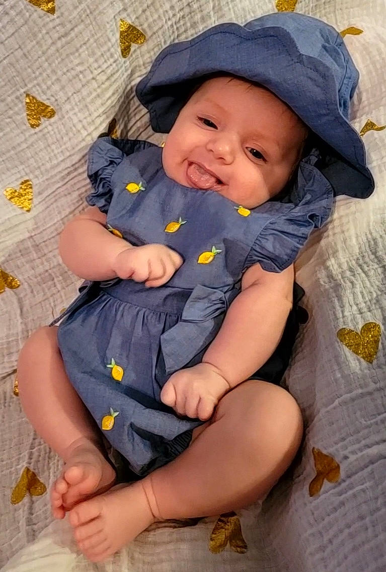 Malena is registered to the contest to win money with this photo: baby, baby_toddler_clothing, cap, cheek, child, comfort, face, finger, foot, fun, happy, hat, head, headwear, human_leg, lap, person, sitting, skin, smile