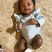 Saige is registered to the contest to win money with this photo: baby, infant, child, smiling, curly_hair, blanket, clothing, socks, lying_down, happy, cute, portrait, indoor, soft_texture, one_person, skin, eyes, hands, legs, cozy