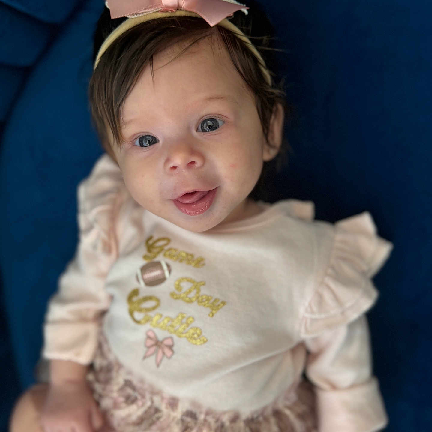 Sakari is registered to the contest to win money with this photo: baby, baby_girl, blue_background, bow, child, clothing, cute, dress, face, fashion, happy, headband, indoor, infant, person, pink, portrait, sitting, smiling, young