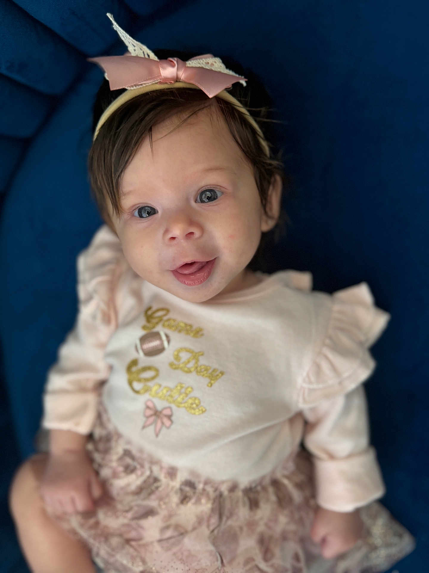 Sakari is registered to the contest to win money with this photo: baby, baby_girl, blue_background, bow, child, clothing, cute, dress, face, fashion, happy, headband, indoor, infant, person, pink, portrait, sitting, smiling, young