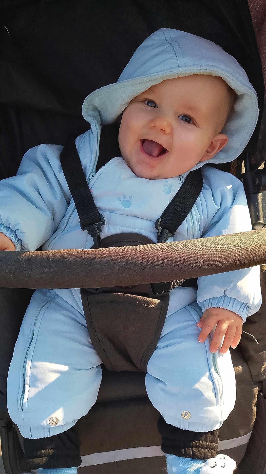 Tiago a rejoint le concours — aidez-le/la à gagner de superbes lots ! baby, child, smiling, hood, snowsuit, stroller, blue_clothing, happy, outdoor, infant, cute, face, warm_clothing, seatbelt, person, toddler, joyful, cold_weather, sitting, hands