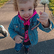 Kayla a rejoint le concours — aidez-le/la à gagner de superbes lots ! toddler, child, denim_jacket, hoodie, dandelion, flower, outdoor, pathway, smiling, curly_hair, sneakers, nature, sunlight, grass, casual_clothing, holding, person, young_child, spring, happy