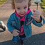 toddler, child, denim_jacket, hoodie, dandelion, flower, outdoor, pathway, smiling, curly_hair, sneakers, nature, sunlight, grass, casual_clothing, holding, person, young_child, spring, happy