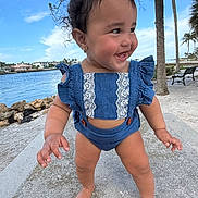 Josiris Isarel is registered to the contest to win money with this photo: toddler, child, smiling, barefoot, blue_outfit, outdoor, water, palm_trees, bench, sand, sunny, happy, cute, portrait, nature, daytime, person, young_child, playful, vacation
