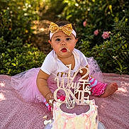 Josiris Isarel joined the competition — help win amazing prizes! baby, birthday, blanket, cake, celebration, child, cute, decorated_cake, face, frosting, gold_bow, greenery, hands, headband, outdoor, party, photography, pink_tutu, sitting, smile