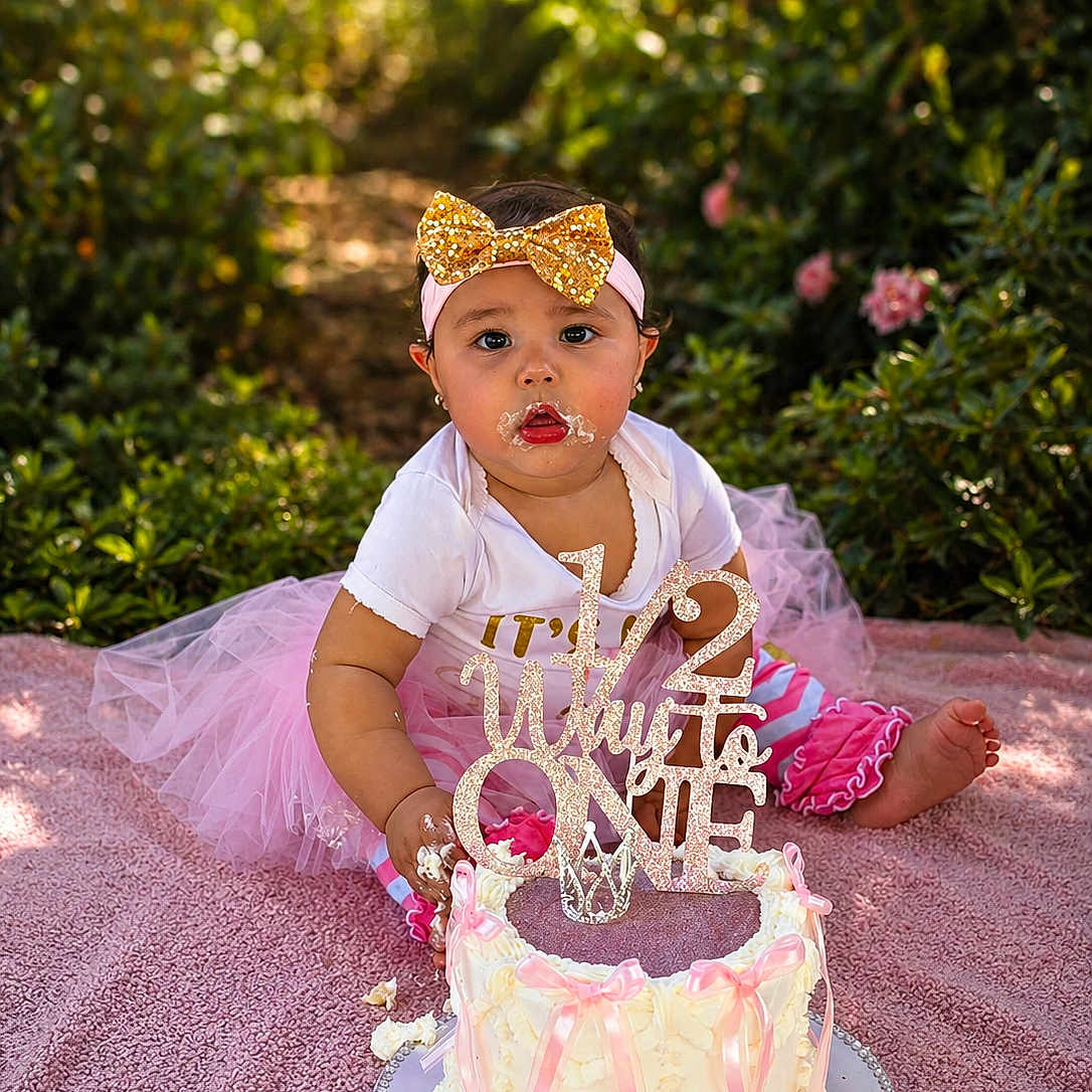 Josiris Isarel joined the competition — help win amazing prizes! baby, birthday, blanket, cake, celebration, child, cute, decorated_cake, face, frosting, gold_bow, greenery, hands, headband, outdoor, party, photography, pink_tutu, sitting, smile