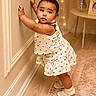 toddler, child, standing, indoor, wall, white_clothing, dress, socks, shoes, carpet, table, flowers, vase, portrait, cute, baby, person, floor, earrings, decor