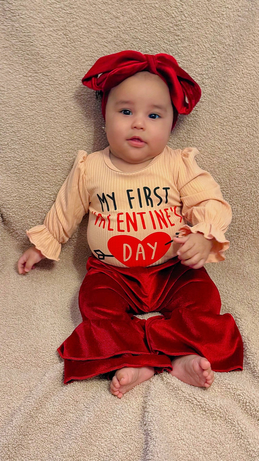 Josiris Isarel joined the competition — help win amazing prizes! baby, bare_feet, blanket, child, chubby_cheeks, cozy, cute, headband, heart_graphic, indoor, infant, portrait, red_bow, ruffled_sleeves, shirt_text, sitting, smiling, toes, valentine, velvet_pants