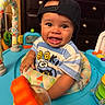 Torrin joined the competition — help win amazing prizes! baby, child, infant, smiling, happy, portrait, cap, backwards_cap, striped_shirt, clothing, activity_center, baby_toy, playroom, indoor, seated, face, eyes, teething, colorful, photograph