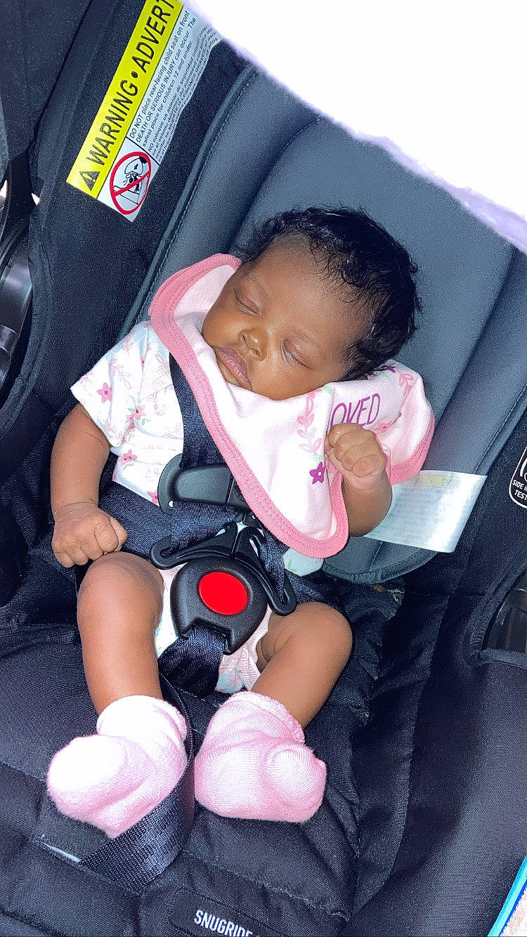 Brooklyn is registered to the contest to win money with this photo: auto_part, baby, baby_carriage, baby_in_car_seat, baby_products, baby_safety, baby_sleeping, baby_toddler_clothing, car_seat, car_seat_cover, child, comfort, finger, lap, leg, person, pink, sitting, thigh, thumb