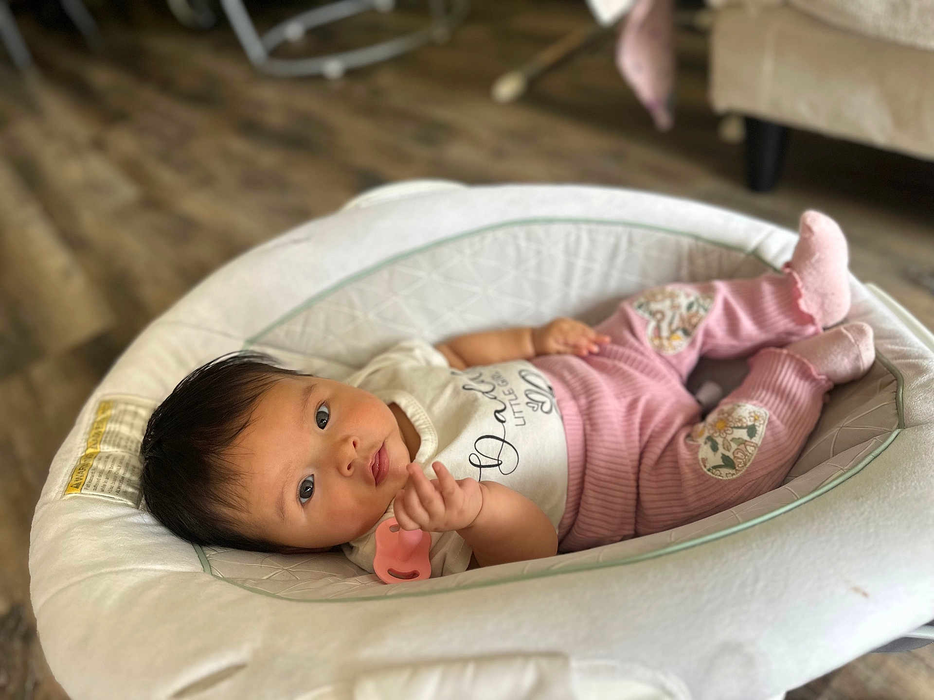 Adalia is registered to the contest to win money with this photo: baby, infant, child, face, pacifier, pink_pants, white_shirt, baby_seat, cushion, flooring, indoors, portrait, cute, looking, expression, soft_focus, clothing, hand, footwear, comfort