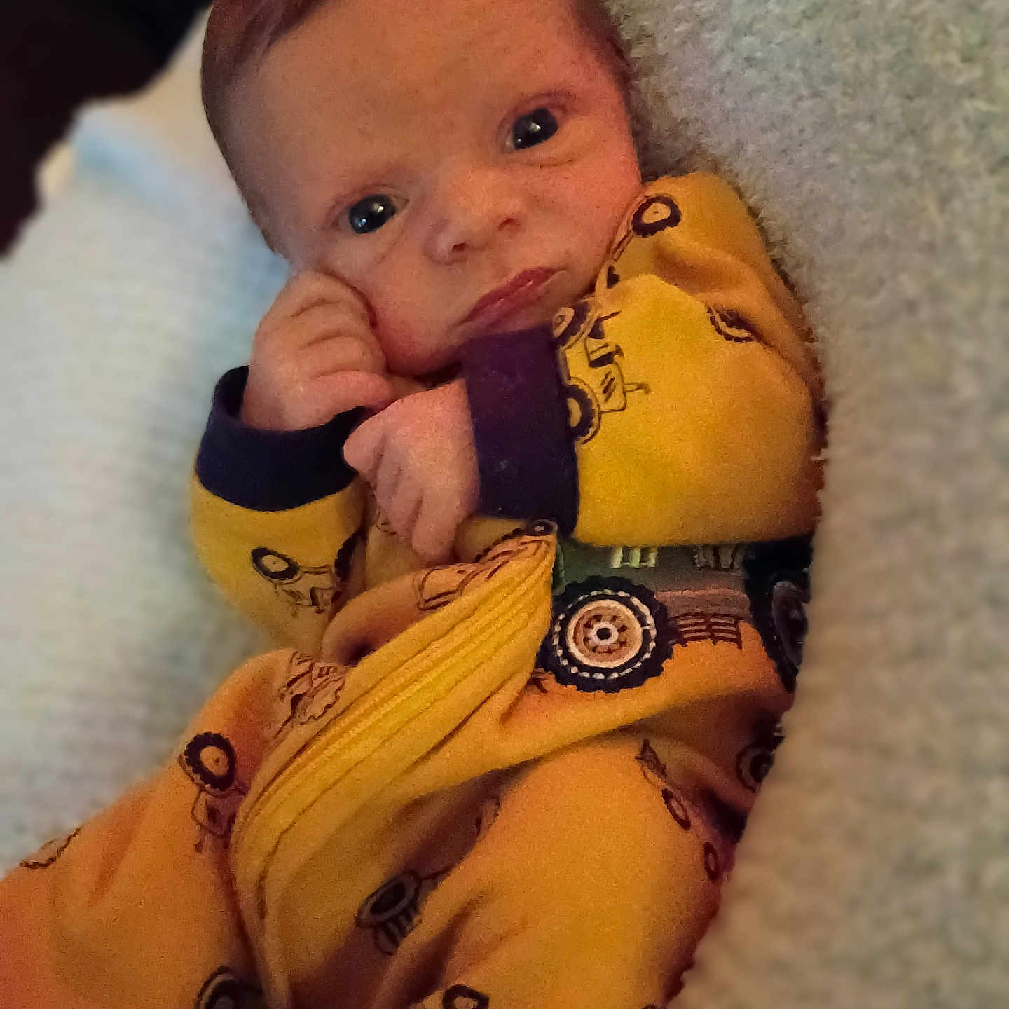 Tyson joined the competition — help win amazing prizes! baby, candid, child, close_up, comfort, cozy, cute, expression, face, hand, indoors, infant, newborn, portrait, resting, sleepwear, soft_blanket, tractor_print, warm_lighting, yellow_onesie