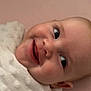 baby, smiling, face, blanket, soft_texture, close_up, infant, happy, cute, portrait, child, wrapped, pink_background, skin, young, expression, lying_down, person, indoors, head