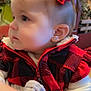 baby, child, red_bow, plaid_jacket, blanket, earring, indoor, portrait, cute, toddler, clothing, face, soft_lighting, holding, young_child, closeup, person, winter_clothes, warm, decorations