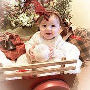Hadley joined the competition — help win amazing prizes! baby, child, red_bow, wagon, holiday, christmas, gift, wrapped_presents, wreath, decorations, carpet, smiling, white_sweater, ball, festive, indoor, cute, holiday_cheer, red, cozy