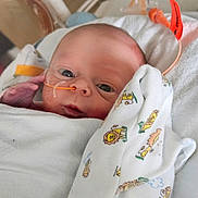 Kora joined the competition — help win amazing prizes! newborn, baby, infant, hospital, medical_tube, blanket, lion_print, face, hand, wrapped, bed, healthcare, cute, small, patient, person, lying_down, closeup, fragile, child