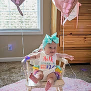 Wrenleigh is registered to the contest to win money with this photo: baby, child, infant, smiling, chair, balloon, pink, headband, ribbon, colorful_clothing, wooden_furniture, carpet, window, sunlight, indoor, celebration, happy, cute, portrait, room