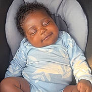 Treasure is registered to the contest to win money with this photo: baby, sleeping, smiling, curly_hair, car_seat, blue_outfit, socks, infant, child, peaceful, cute, cozy, clothing, toddler, resting, seat_belt, indoors, portrait, young_child, relaxed