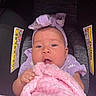 baby, infant, car_seat, blanket, pink, purple, headband, clothing, cute, child, person, portrait, seat, warning_label, soft_texture, indoor, closeup, holding, young, face