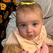 Dolcie is registered to the contest to win money with this photo: baby, blue_eyes, child, close_up, clothing, cute, fabric, gray_clothing, halloween, holding, indoor, infant, knitted_blanket, person, pink_blanket, portrait, pumpkin_pattern, sweatshirt, yellow_bow, young_child