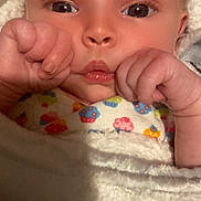 Bella joined the competition — help win amazing prizes! baby, infant, close_up, face, hands, blanket, clothing, colorful, cute, wrapped, soft_texture, skin, expression, newborn, portrait, indoors, child, young, person, cozy