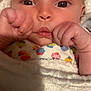baby, infant, close_up, face, hands, blanket, clothing, colorful, cute, wrapped, soft_texture, skin, expression, newborn, portrait, indoors, child, young, person, cozy