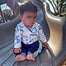 toddler, child, slide, playground, outdoor, sunlight, barefoot, tree, hand, clothing, pants, long_sleeve, expression, park, daylight, nature, play, young_child, casual, sitting
