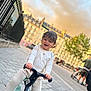 child, toddler, scooter, outdoor, sidewalk, city, buildings, pajamas, happy, smile, play, toy, street, urban, daylight, person, casual, fun, young, transport