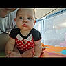 Charlie joined the competition — help win amazing prizes! baby, infant, child, polka_dot, red_clothing, black_clothing, play_mat, indoor, person, face, expression, adult_partial, pout, colorful, toy, floor, curious, closeup, candid, portrait