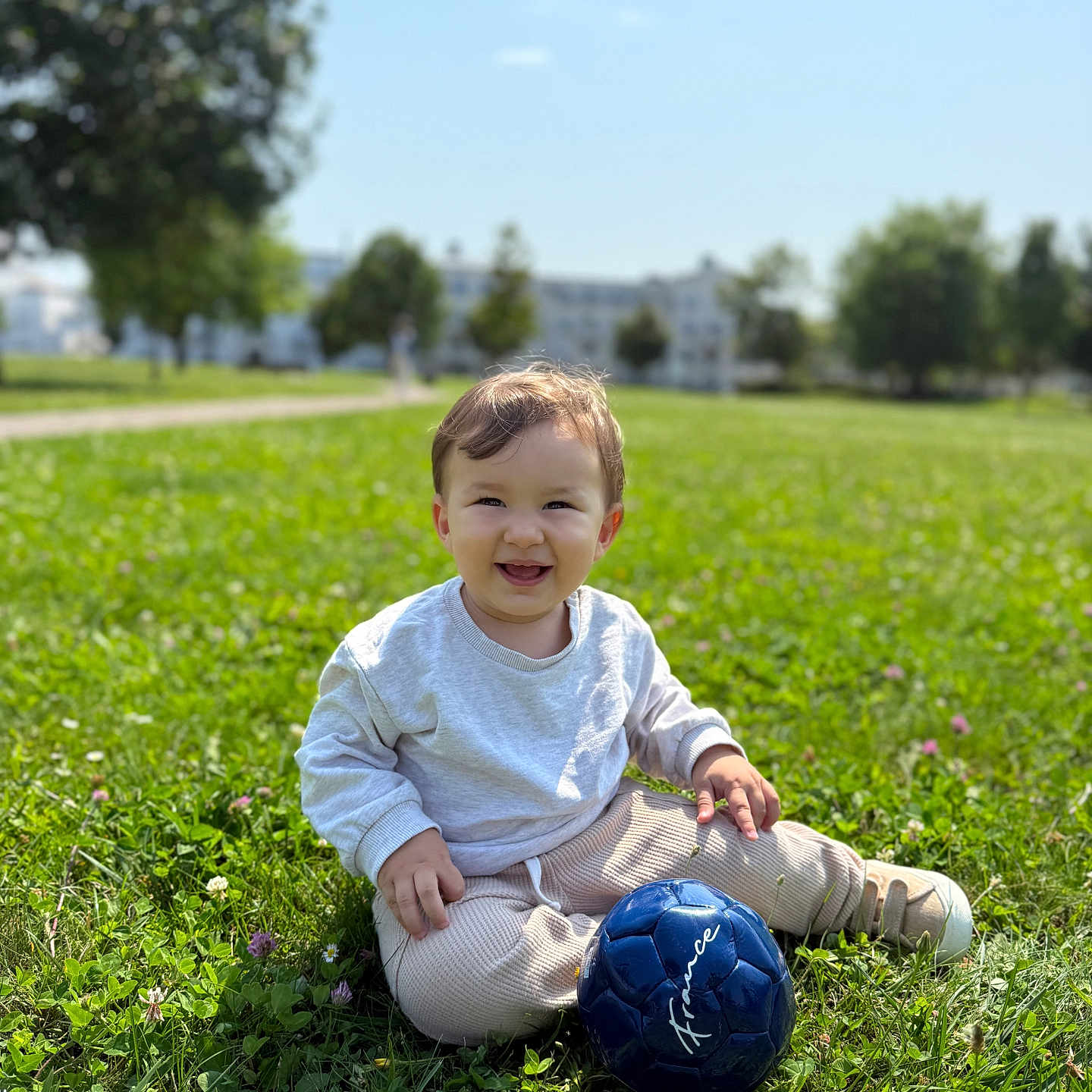 Arslan a rejoint le concours — aidez-le/la à gagner de superbes lots ! blue_ball, casual_clothing, child, cute, daylight, grass, greenery, happy, nature, outdoor, park, person, playing, recreation, sitting, smile, soccer_ball, sunny_day, toddler, young_child