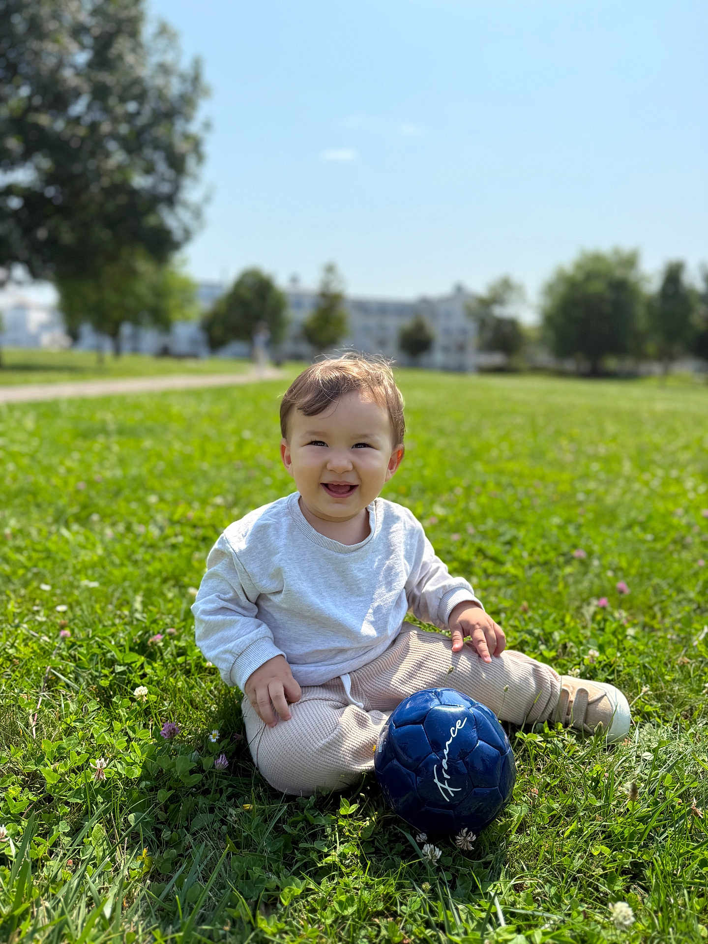 Arslan a rejoint le concours — aidez-le/la à gagner de superbes lots ! toddler, child, grass, outdoor, smile, soccer_ball, blue_ball, sunny_day, greenery, casual_clothing, sitting, happy, playing, park, nature, young_child, daylight, cute, person, recreation