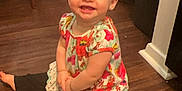 Joani is registered to the contest to win money with this photo: toddler, child, smiling, sitting, floor, wooden_floor, indoor, clothing, colorful, leggings, top, barefoot, face, happy, person, home, chair, backpack, earring, young_child