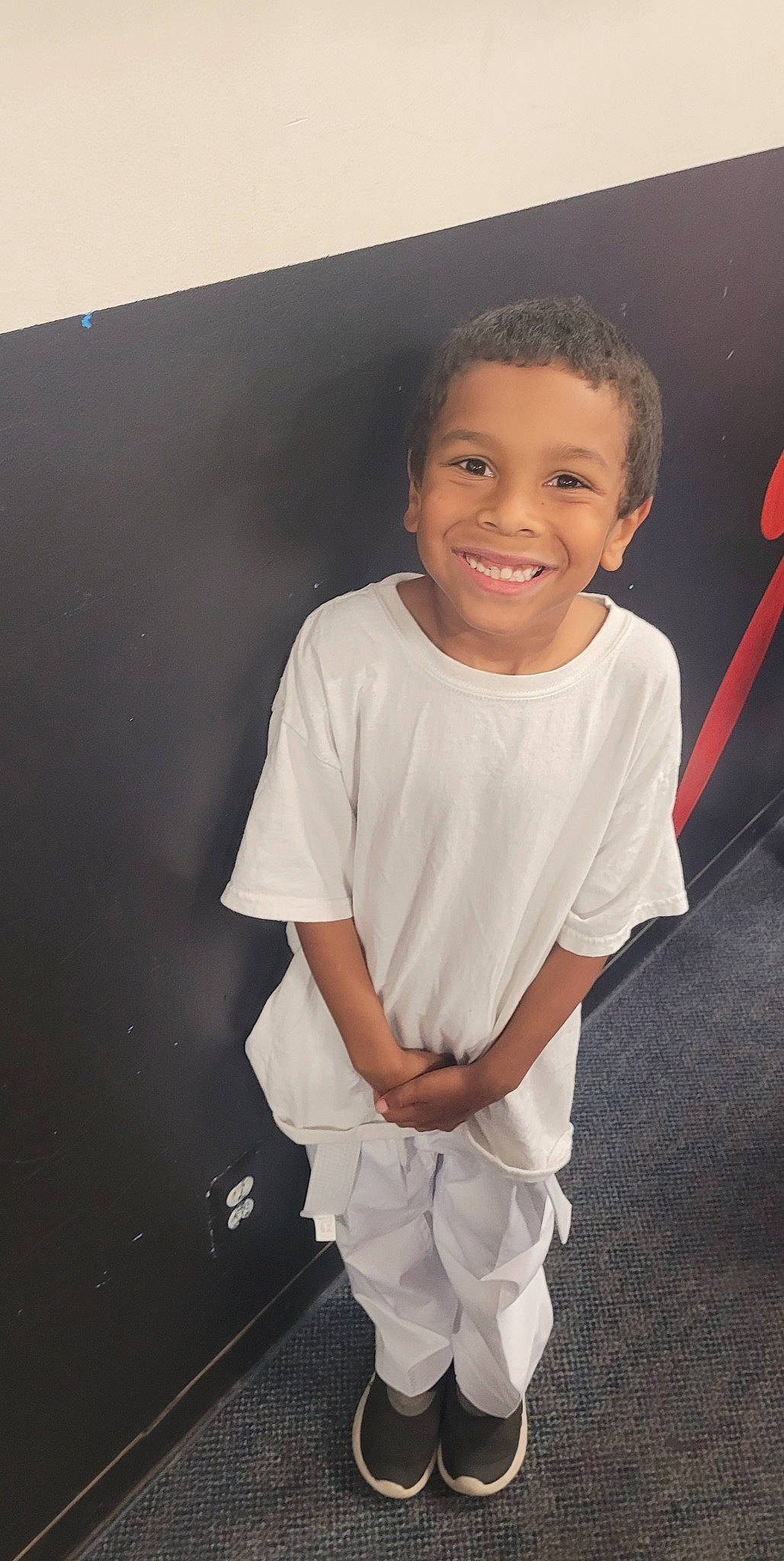 Izaiah is registered to the contest to win money with this photo: arm, child, child_model, cool, fashion_design, flash_photography, flooring, formal_wear, fun, gesture, happy, joy, person, room, shoulder, sitting, sleeve, smile, t_shirt, toddler